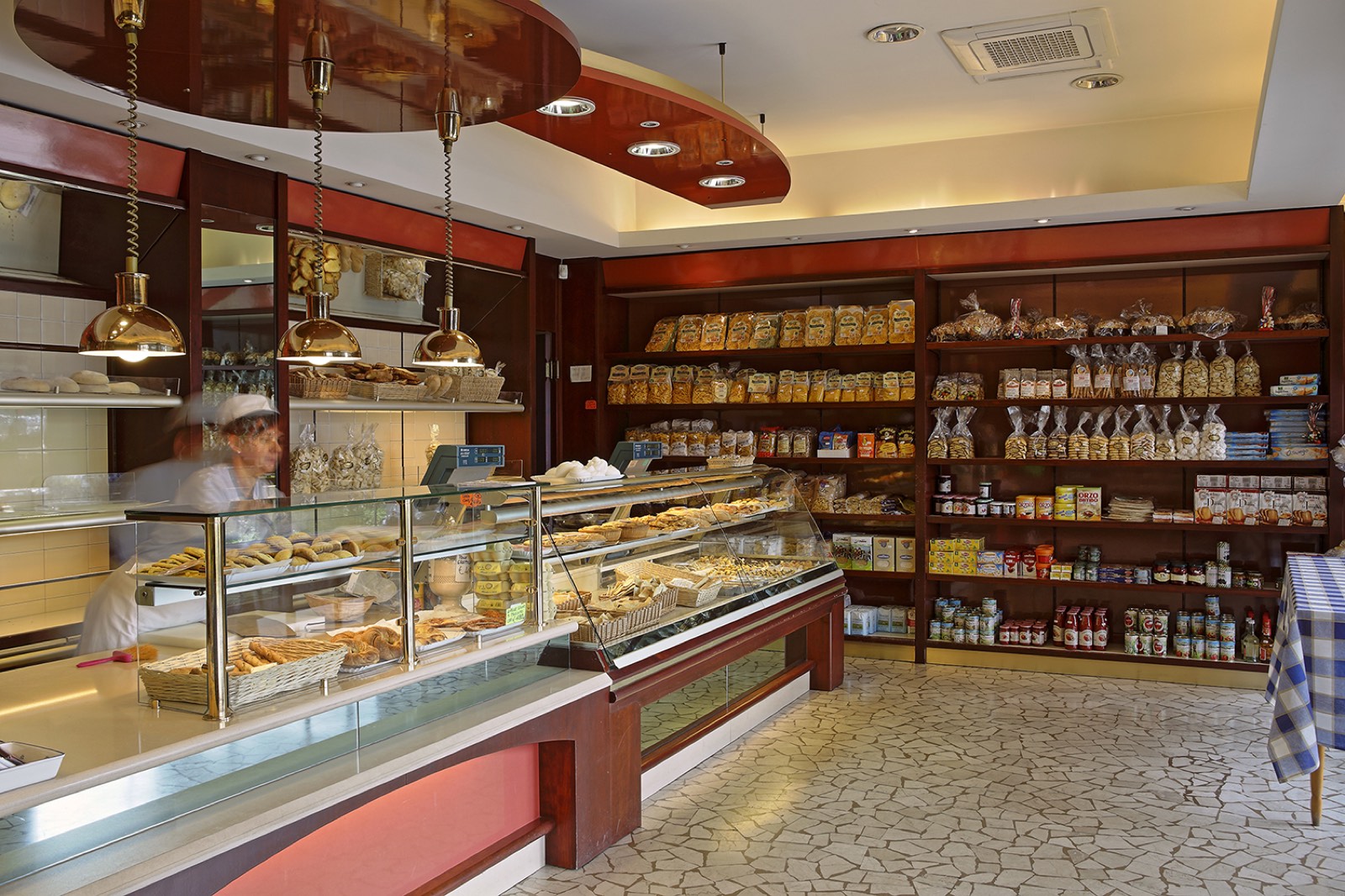 L'interno del Forno Cassari: bancone in vetro, pane e prodotti da forno, scaffali di pasta e conserve